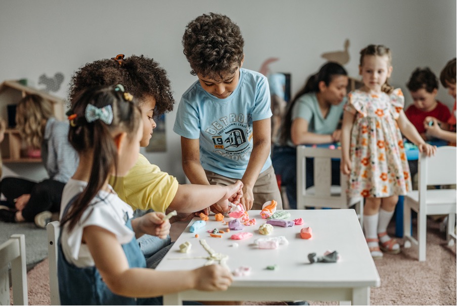 Professionnelle de la petite enfance observant avec attention les interactions entre plusieurs jeunes enfants lors d'un temps de jeu.